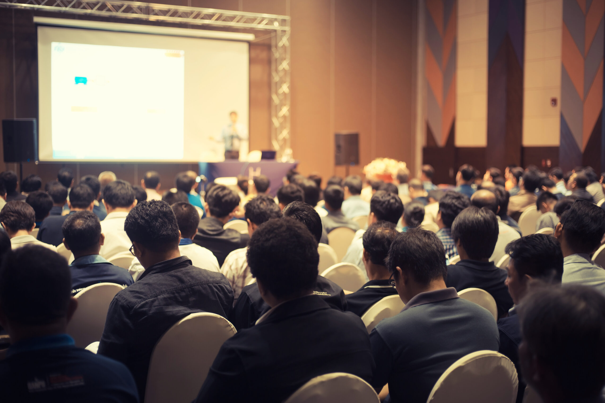 Group of people in a convention center watching a presentation